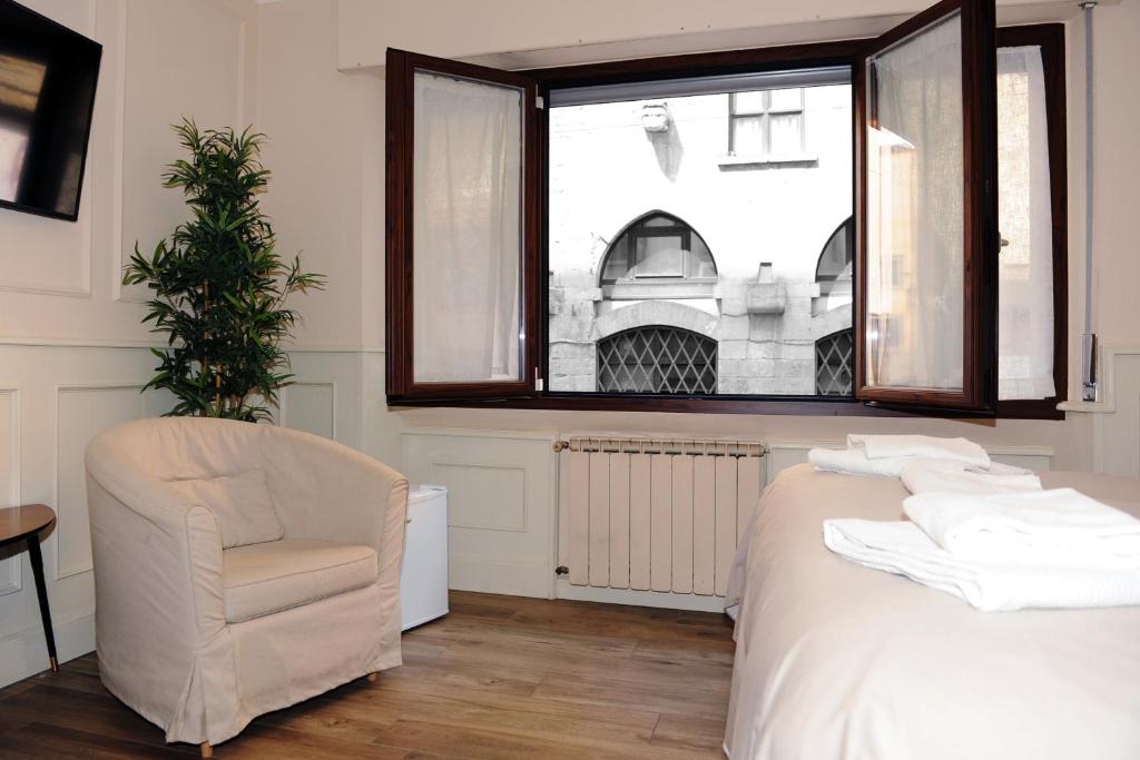 a bedroom with a bed and a chair and a window at pontevecchio rooms in Florence