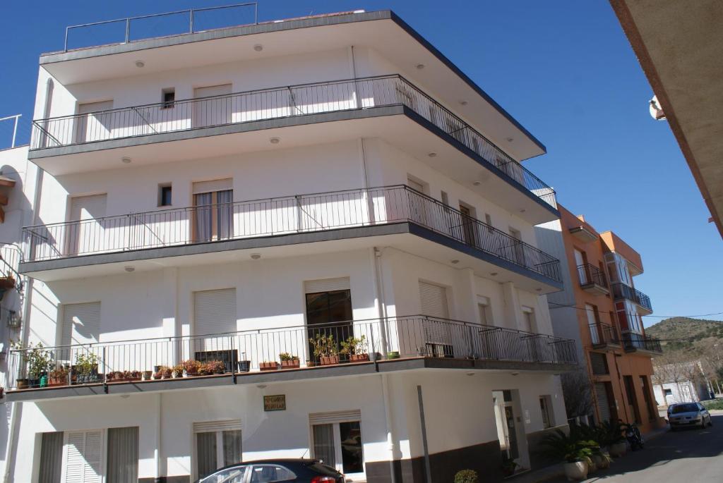 a white building with balconies on a street at Hostal Gran Sol in Llança