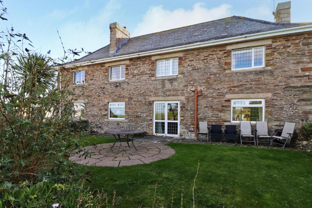 a brick house with a table and chairs in the yard at WALK TO THE BEACH, spacious cottage with sea views in Saint Merryn