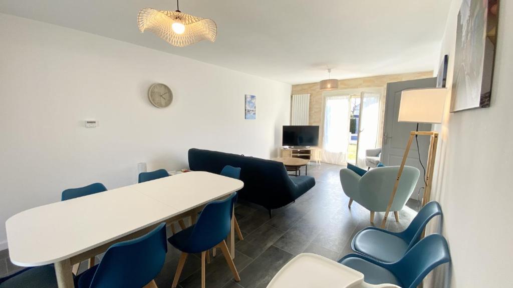 uma sala de estar com uma mesa branca e cadeiras azuis em Chez Sandrine & Tanguy em Saint-Valery-sur-Somme