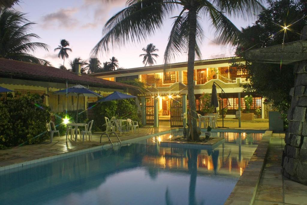 a hotel with a swimming pool in front of a building at Pousada Shalom Beach in Maragogi