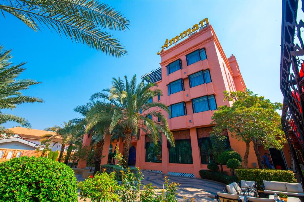 a pink building with palm trees in front of it at Amman Unique Hotel in Udon Thani