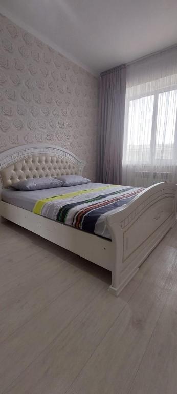 - un lit blanc dans une chambre avec fenêtre dans l'établissement Апартаменты в новом ЖК АРМАНЕ, à Aqtöbe