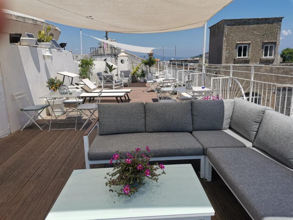 a rooftop patio with a couch and tables and chairs at Le Volte Procida Home in Procida