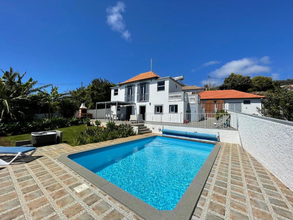 a swimming pool in front of a house at Tranquilidade in Estreito da Calheta