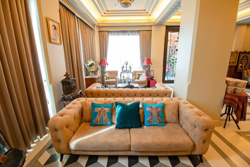 a living room with a brown couch with blue pillows at Amman Unique Hotel in Udon Thani