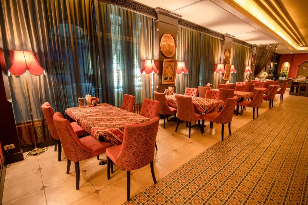 a dining room with tables and chairs and curtains at Amman Unique Hotel in Udon Thani