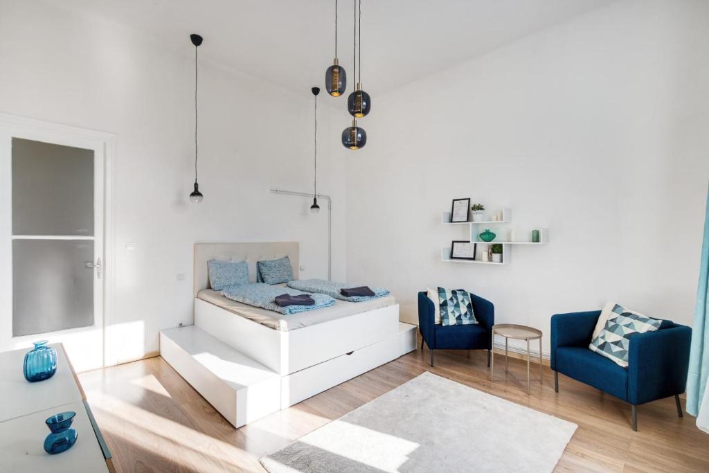 a bedroom with a bed and two blue chairs at Elizabeth Garden Apartment in Budapest