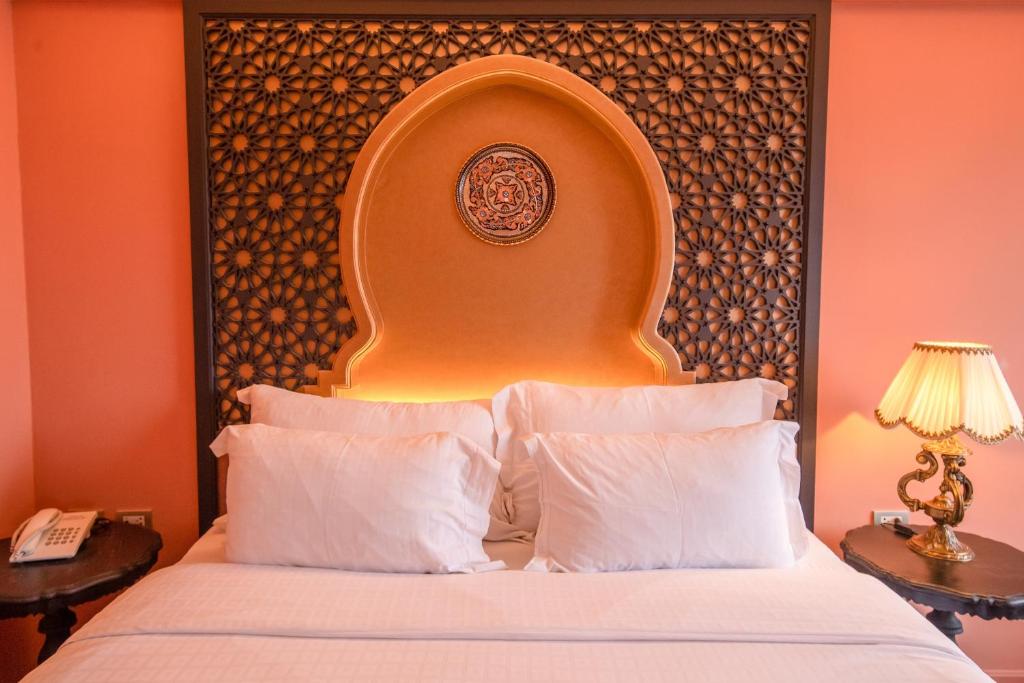 a hotel room with a bed with a large headboard at Amman Unique Hotel in Udon Thani