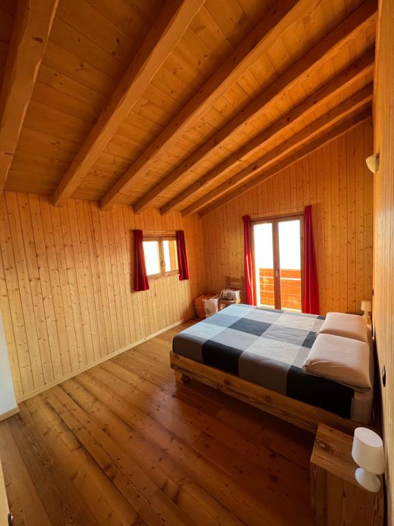 1 dormitorio con 1 cama en una habitación de madera en Baita “Oasi della Volpe” en Cà Paini