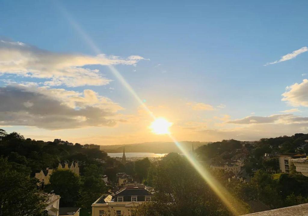 a view of the sun setting over a city at Top Floor Apartment Overlooking Torquay Harbour Pet Friendly in Torquay