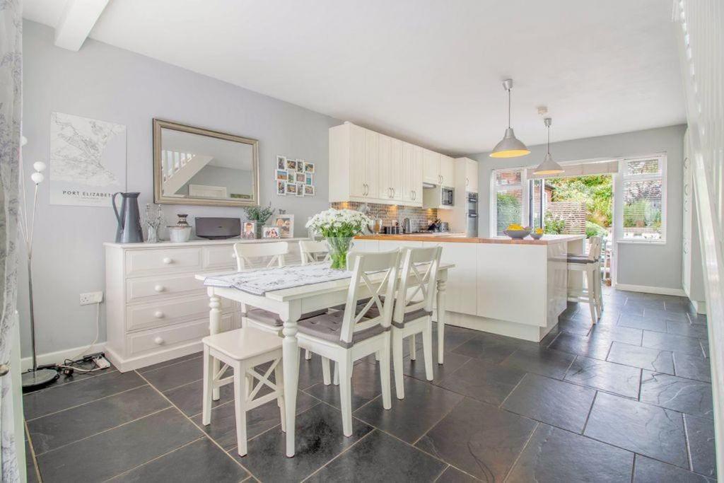 a kitchen with a white table and white chairs at Pear Tree House in Beeston