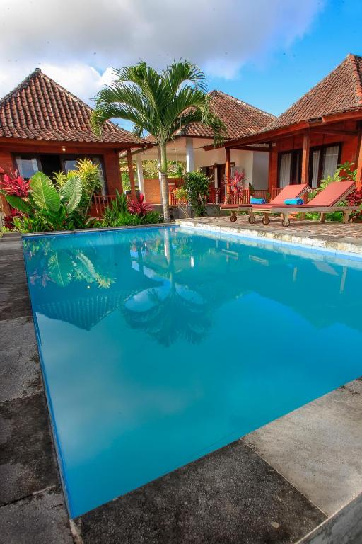a blue swimming pool in front of a house at THE DARA HILL in Nusa Penida