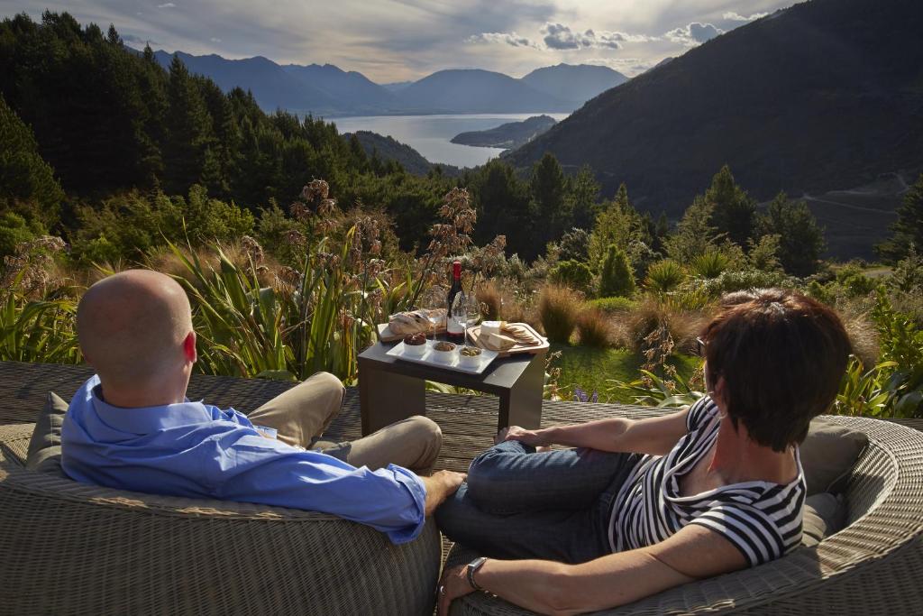 
a man and a woman sitting on a bench at The Alpine Retreat in Queenstown
