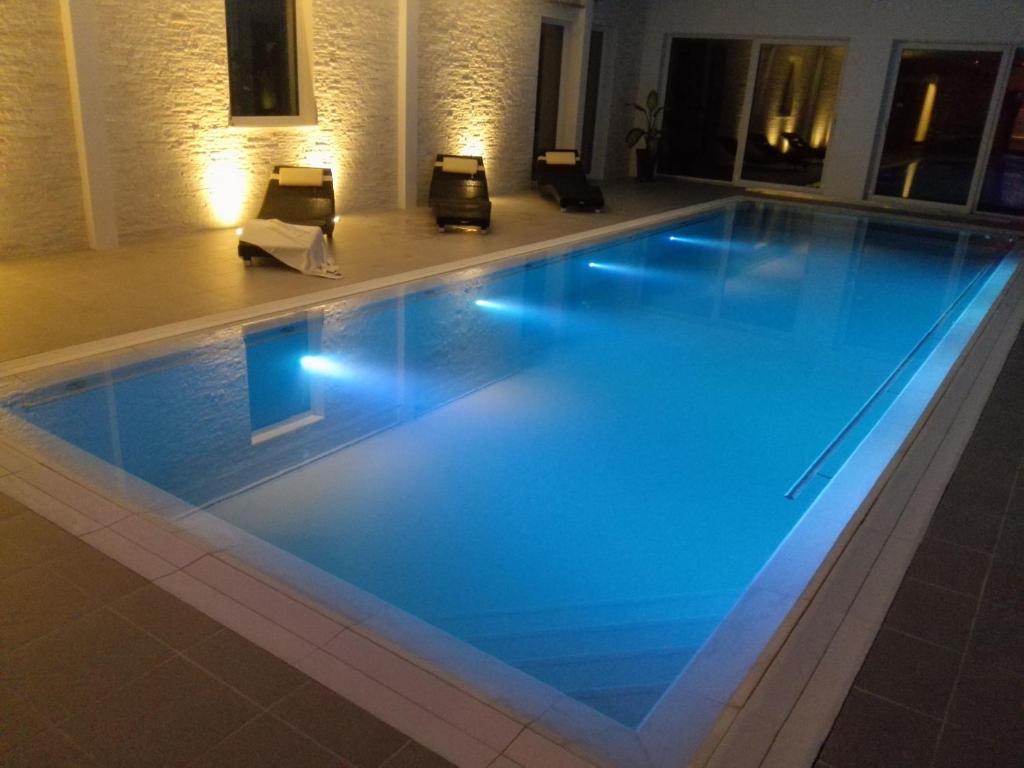a swimming pool in a hotel with blue lighting at My Cocoon in Court-Saint-Étienne