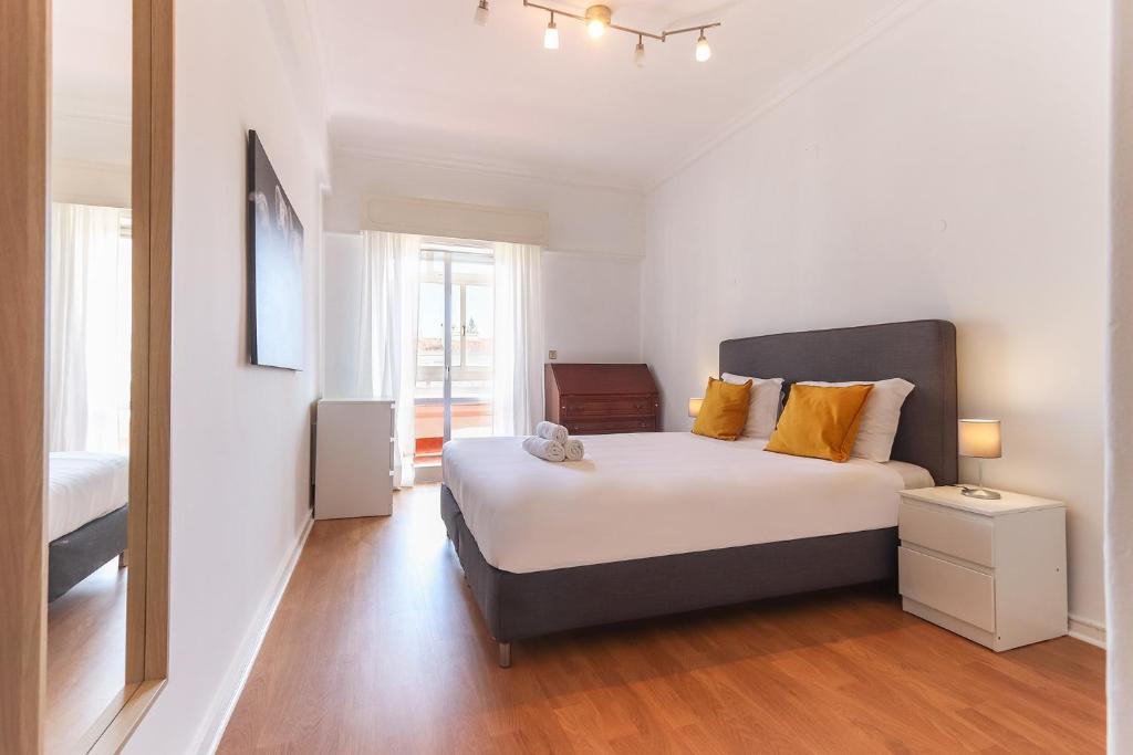 ein Schlafzimmer mit einem großen Bett mit gelben Kissen in der Unterkunft Oeiras Balcony by Homing in Oeiras