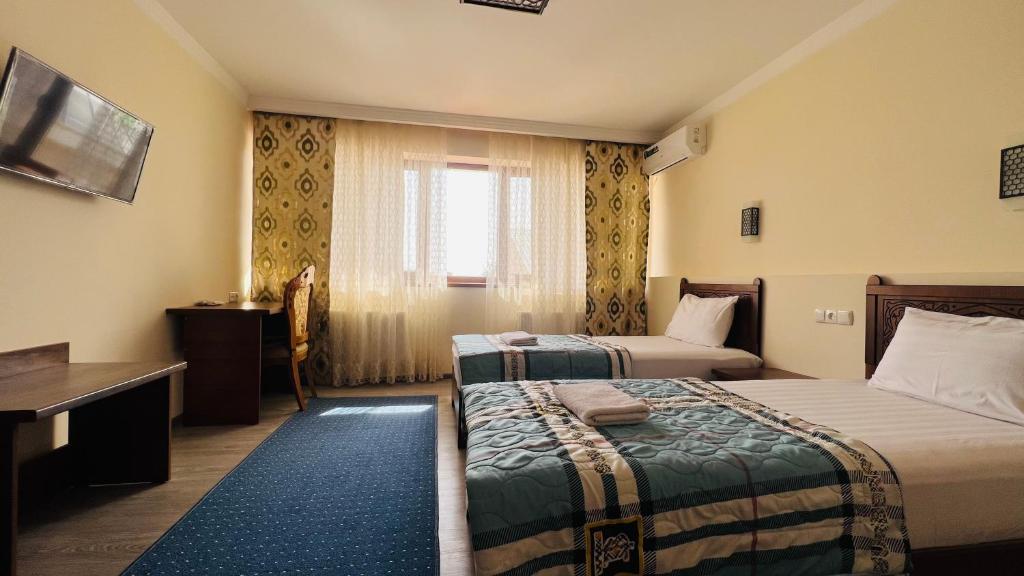 a hotel room with two beds and a window at 2nd floor in Bukhara