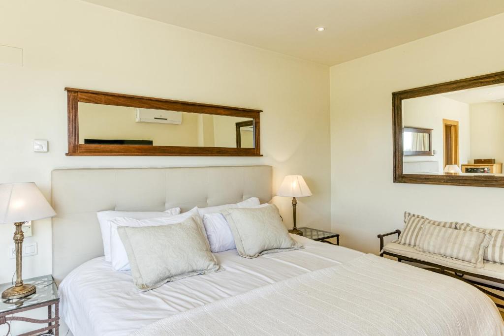 1 dormitorio con 1 cama blanca grande y espejo en Luxury Golf Villa Torremirona, en Navata