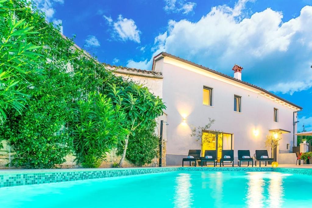 a villa with a swimming pool in front of a house at VILLA LATINI - Ideal for a family vacation. Heated pool. Local breakfast optional available in Svetvinčenat