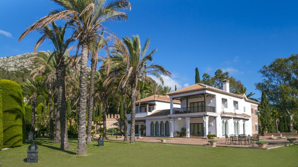 a large white house with palm trees in front of it at Cubo's Mountain Bayview Luxury Villa in Málaga