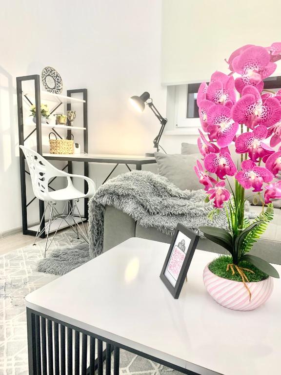 salon z białym stołem i różowymi kwiatami w obiekcie - Enjoy Cozy Apartment, Close To City Center - w Taszkiencie