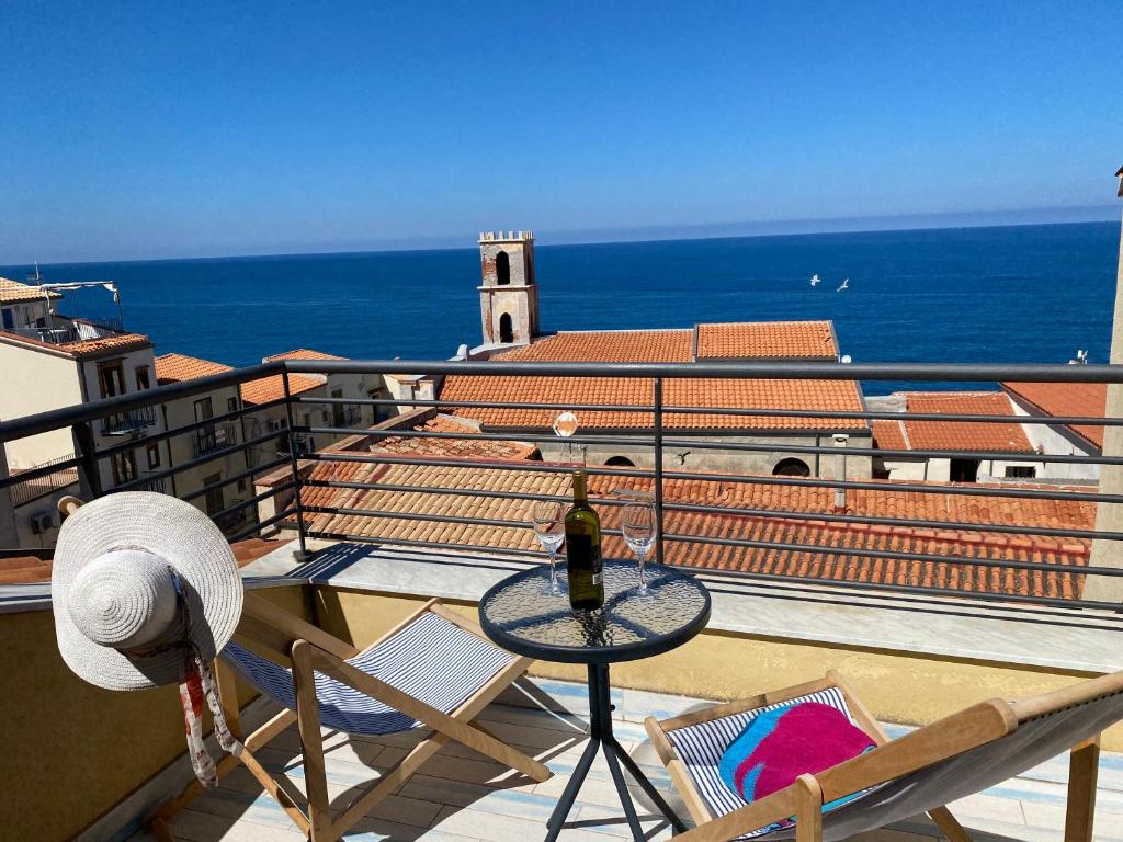een tafel en stoelen op een balkon met uitzicht op de oceaan bij Dolce Estate Cefalù in Cefalù