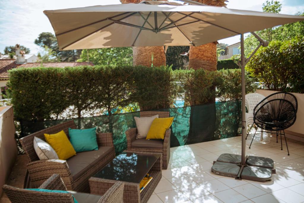 une terrasse avec un canapé et un parasol dans l'établissement Martine & Thomas Santa Lucia, à Saint-Raphaël