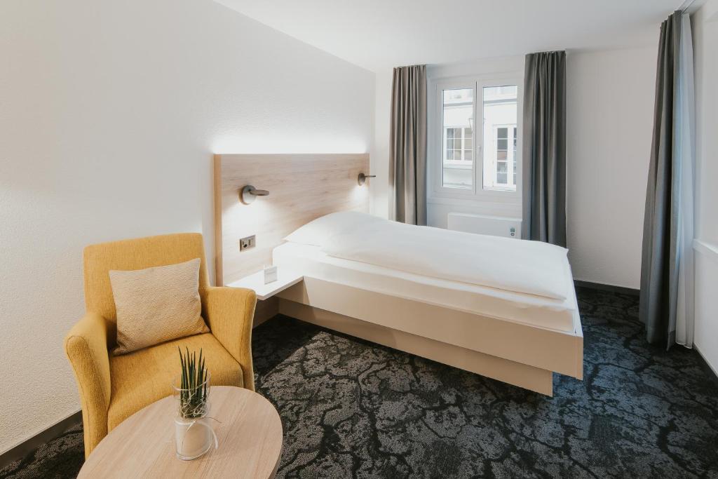 una camera d'albergo con letto, sedia e tavolo di Gartenhaus by Ochsen Lenzburg a Lenzburg
