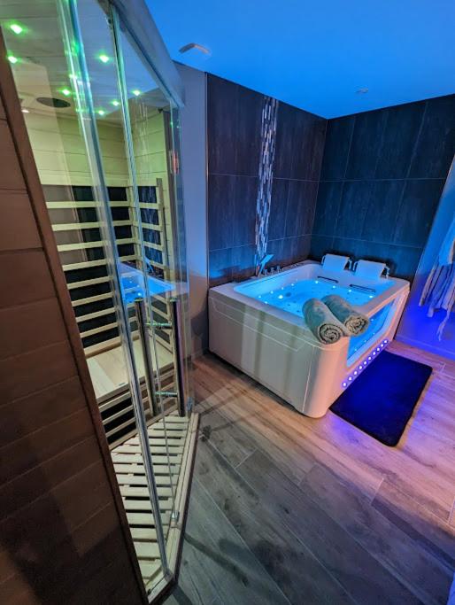 Elle comprend une grande salle de bains pourvue d'une baignoire et d'un plafond bleu. dans l'établissement Déliv'Love, à Douvres-la-Délivrande