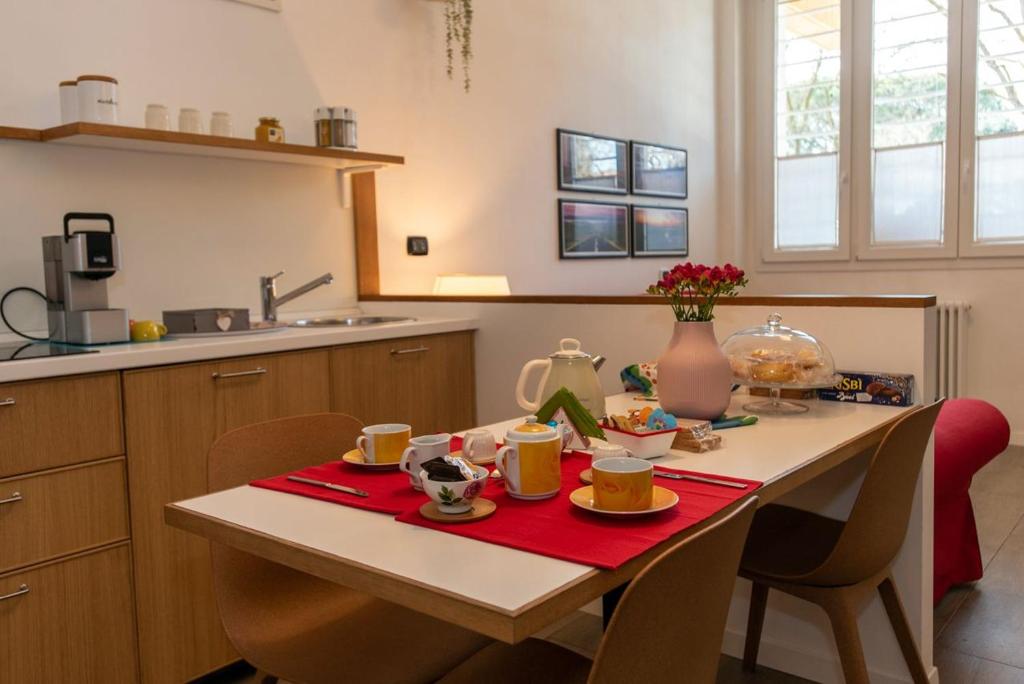 una cocina con una mesa con tazas y platos. en La dimora di Amélie-Self Check in-Parcheggio gratuito, en San Lazzaro di Savena