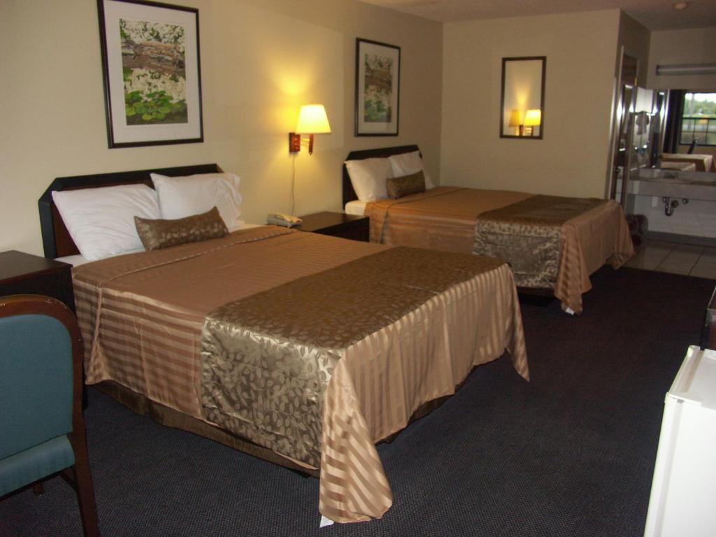 una habitación de hotel con 2 camas y una silla en Deerwood Inn & Madison Campground, en Madison