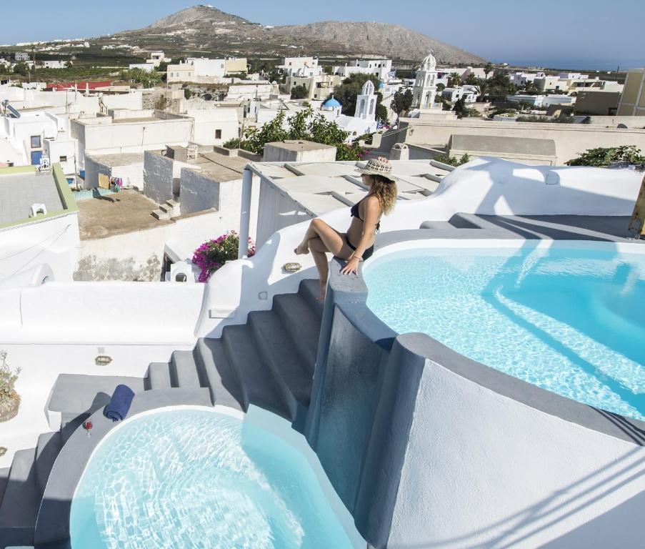 a woman sitting on a stairs next to a swimming pool at Simantiri Private Villa in Megalochori