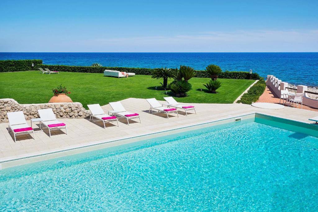 una piscina con sillas y vistas al océano en Blue Moon, en Fontane Bianche