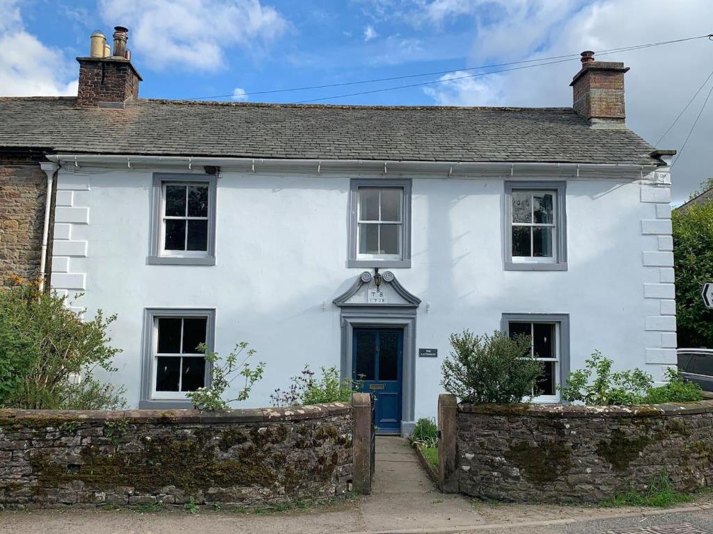 uma casa branca com uma porta azul em Stunning 4-bed Grade II house in the Lake District em Wigton