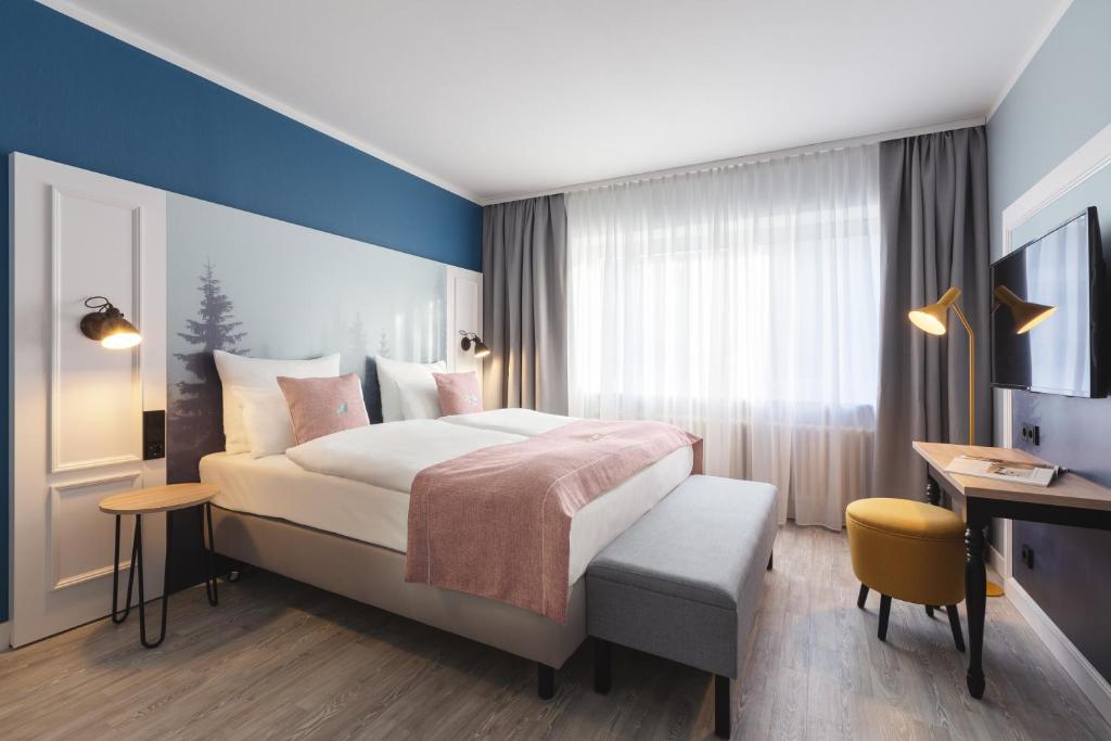 エッセンにあるYggotel Solsortの大きなベッドとデスクが備わるホテルルームです。