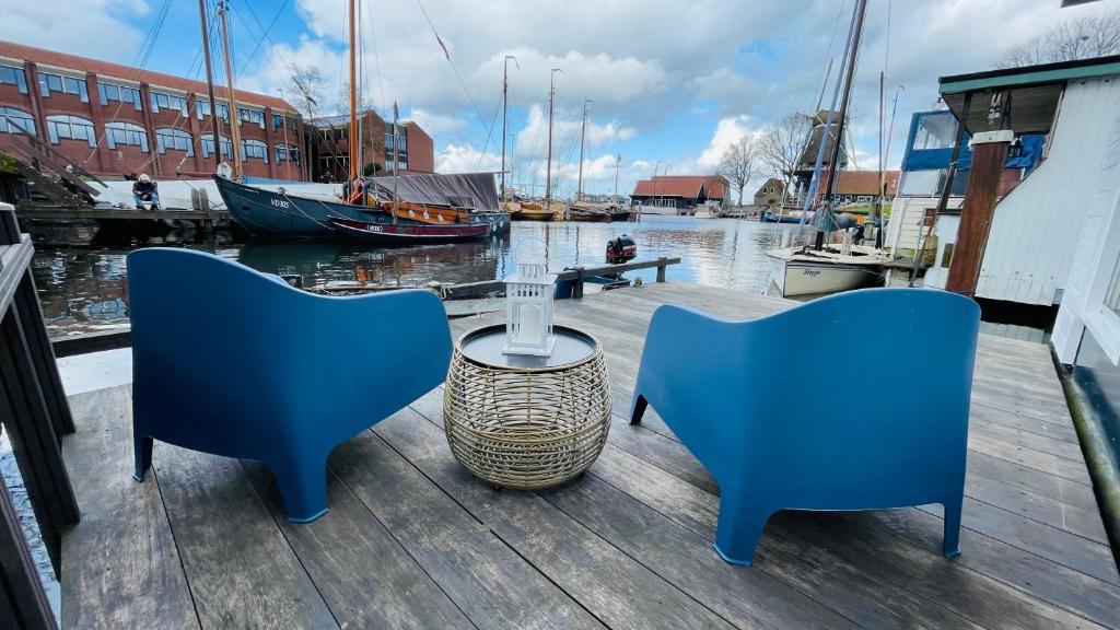 two blue chairs and a table on a dock with boats at Woonboot 4 Harderwijk in Harderwijk