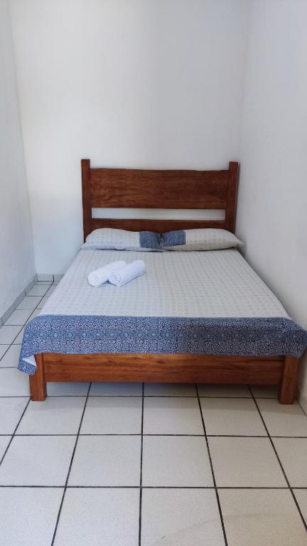a bed with a wooden frame in a room at Pousada Maia in Itaúnas