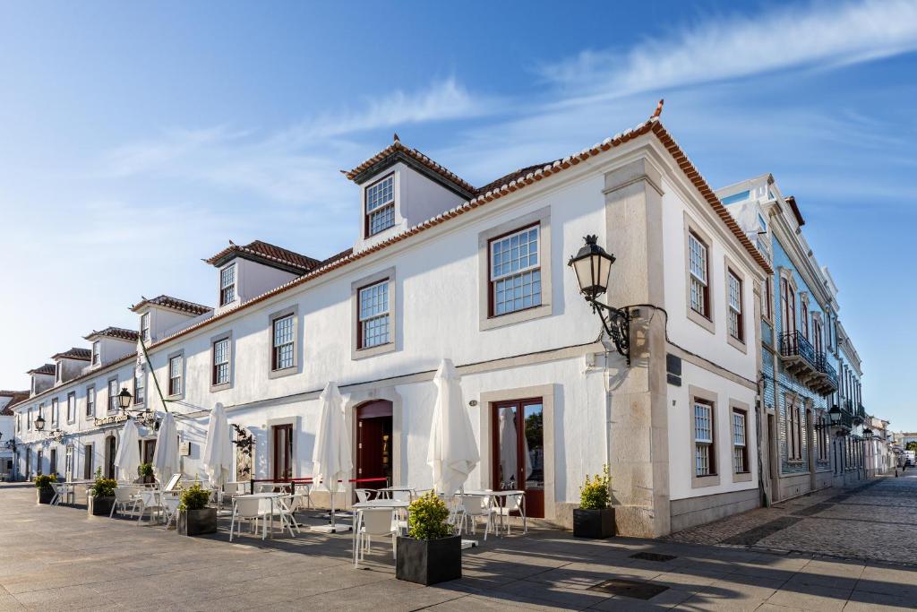 a large white building with tables and chairs on a street at Pousada Vila Real Santo Antonio in Vila Real de Santo António