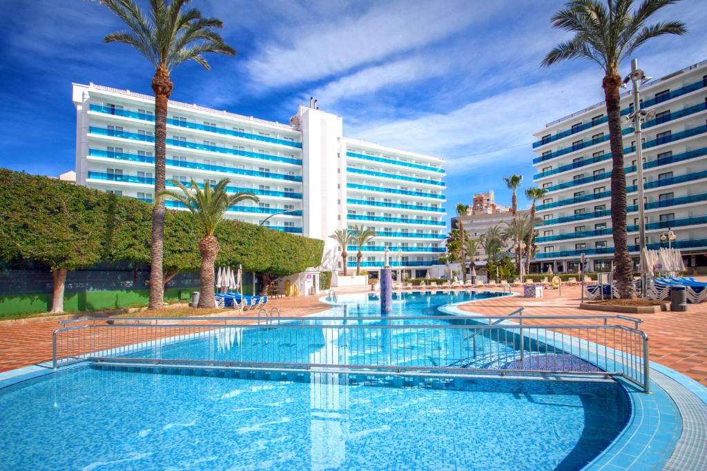 una gran piscina con palmeras y un edificio en Hotel Servigroup Venus, en Benidorm