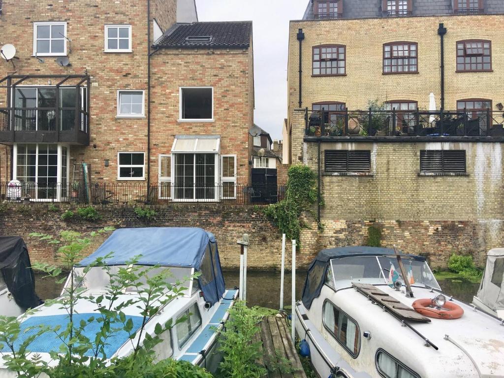 two boats docked in a canal in front of buildings at River Penthouse Apartment In The Heart of in Saint Neots