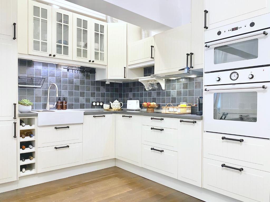 uma cozinha branca com armários brancos e electrodomésticos em aço inoxidável em Vintage Top Centre Apartment em Sófia
