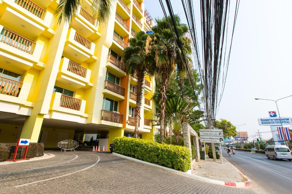 a yellow building with palm trees in front of a street at Mykonos Condo in Hua Hin