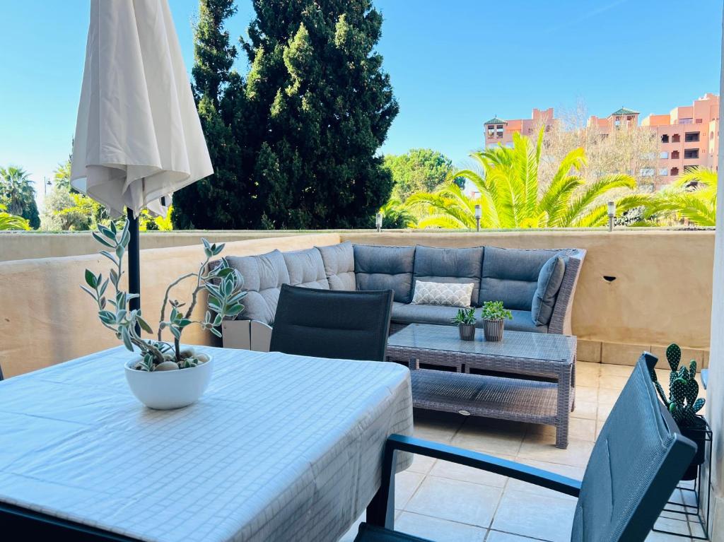 un patio con mesa, sofá y sombrilla en Los Jardines Isla Canela, en Huelva