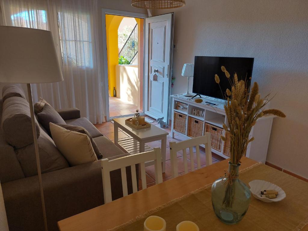uma sala de estar com um sofá e uma mesa em Aldea Playa Golf 2 dormitorios em Huelva