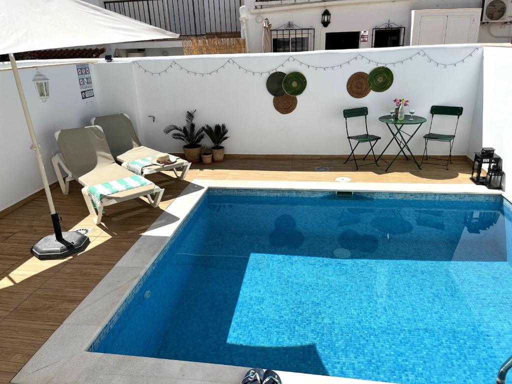 a blue swimming pool with chairs and a table at Nerja Paradise Rentals - Villa Zafiro in Nerja