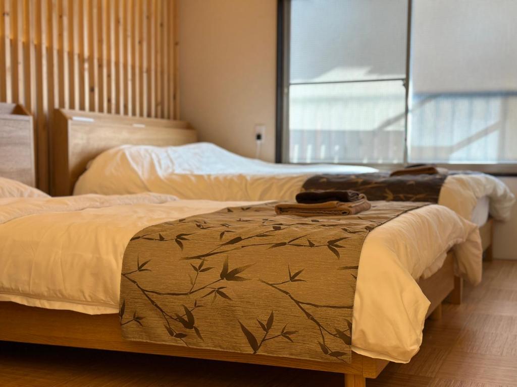 2 bedden in een slaapkamer met een raam bij 巡 in Osaka