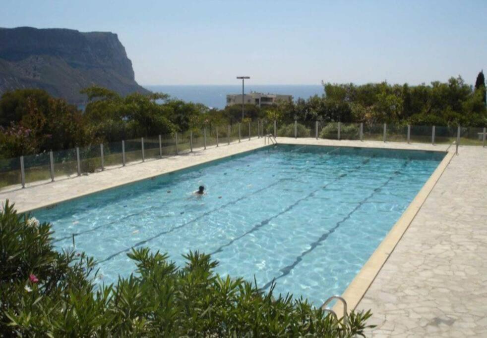 uma pessoa nadando em uma grande piscina em Superbe appartement piscine, tennis, vue mer et décoré avec goût em Cassis