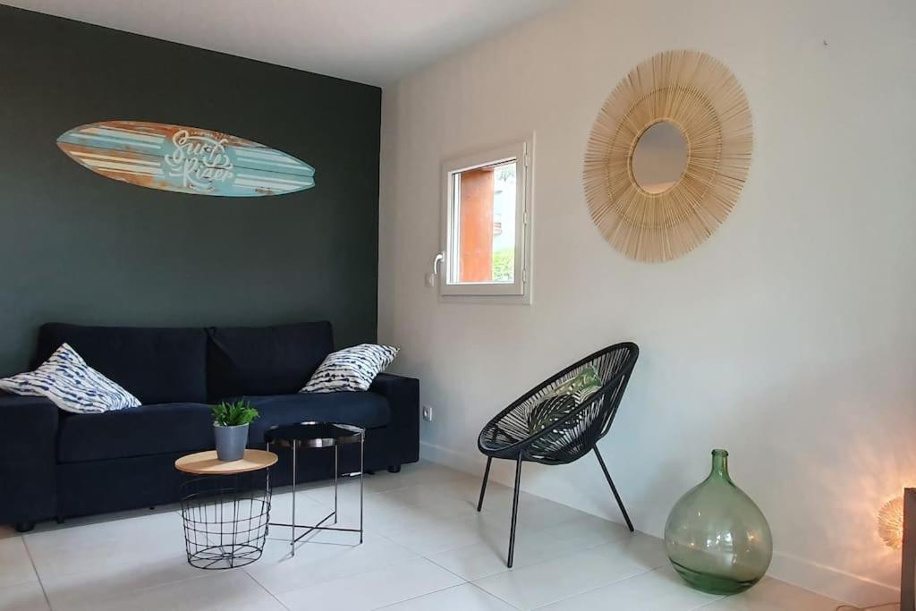 een woonkamer met een bank en een tafel en stoelen bij Résidence Escale Océane T2 42 m2 à 500 m de la Plage in Capbreton