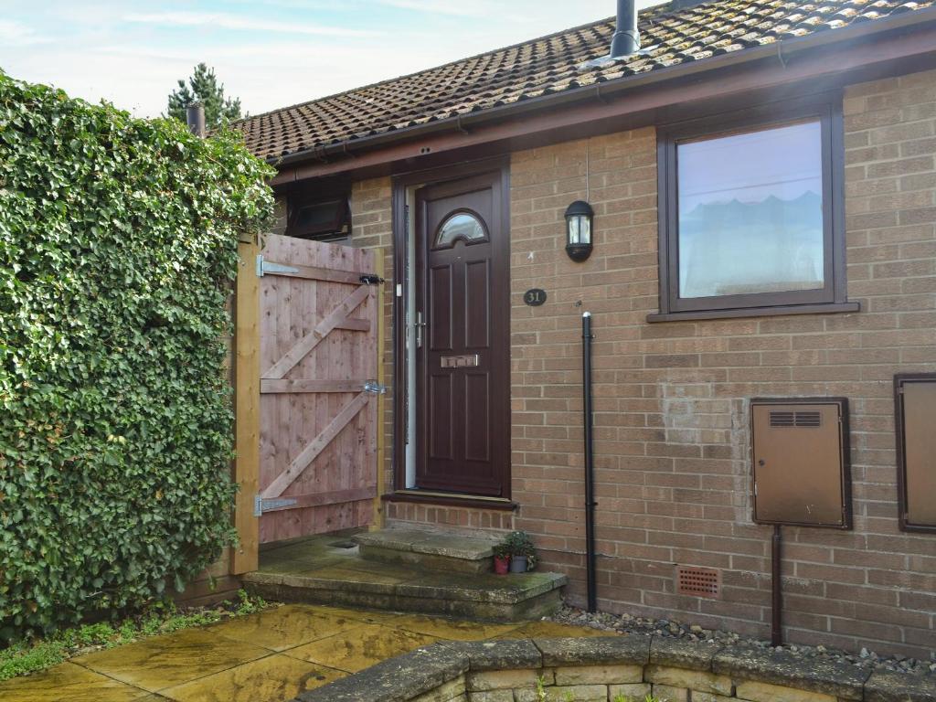 a house with a wooden door and a hedge at Hill Rise in Pocklington