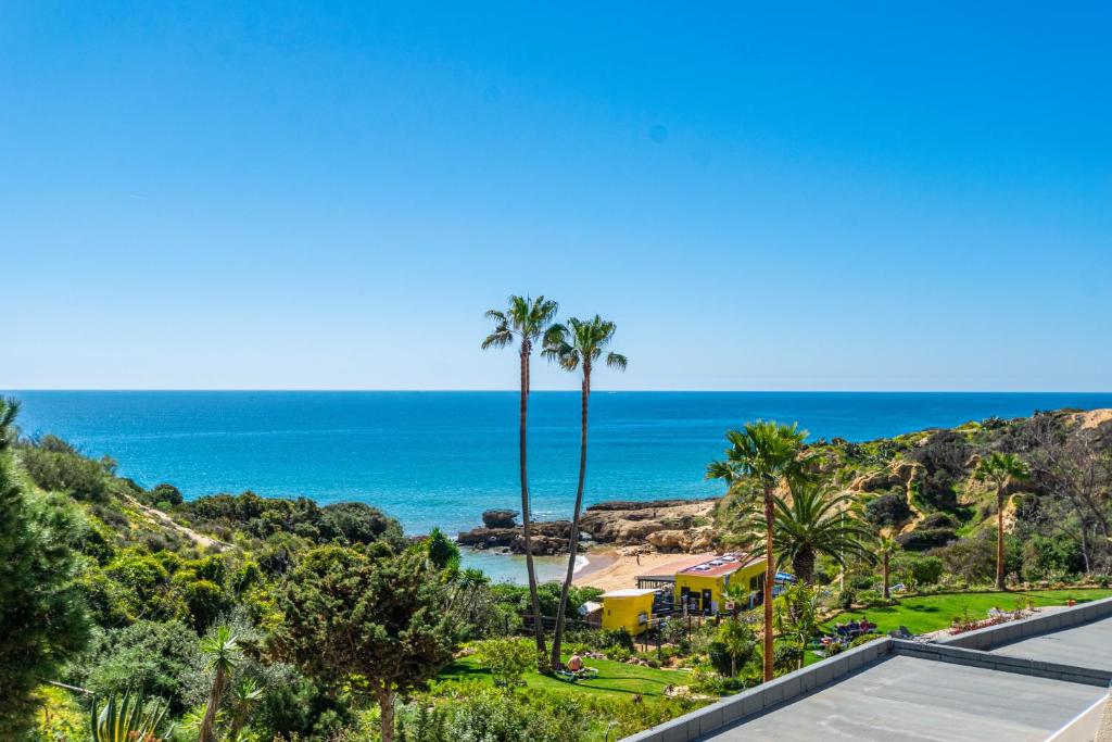- une vue sur une plage avec des palmiers et une maison dans l'établissement BeGuest Aveiros Beach View Apartment, à Albufeira